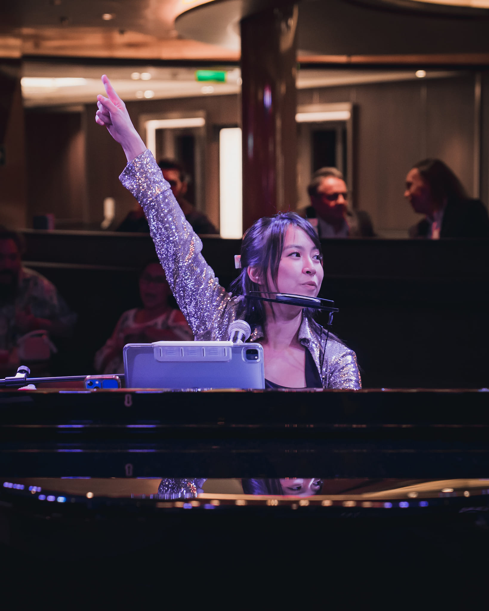 Tammy singing at the piano with one hand raised to the audience